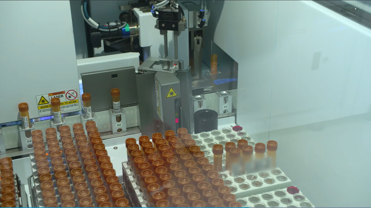 臨床ラボ内の試験管と、背景のロボット アームの画像